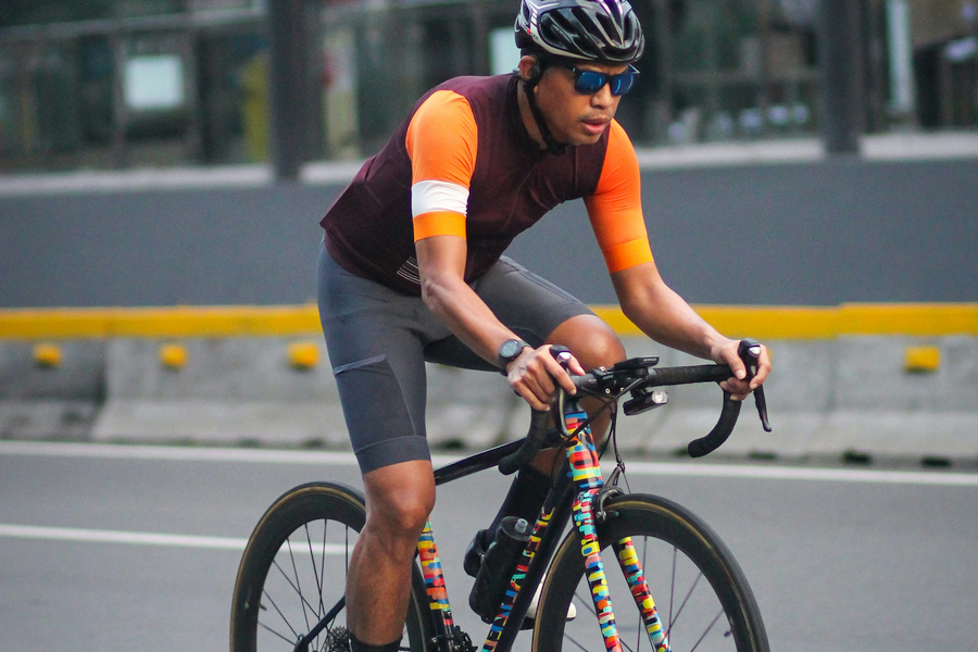 A male cyclist in full gear riding a bike on a city street, focusing on safety and proper cycling posture.